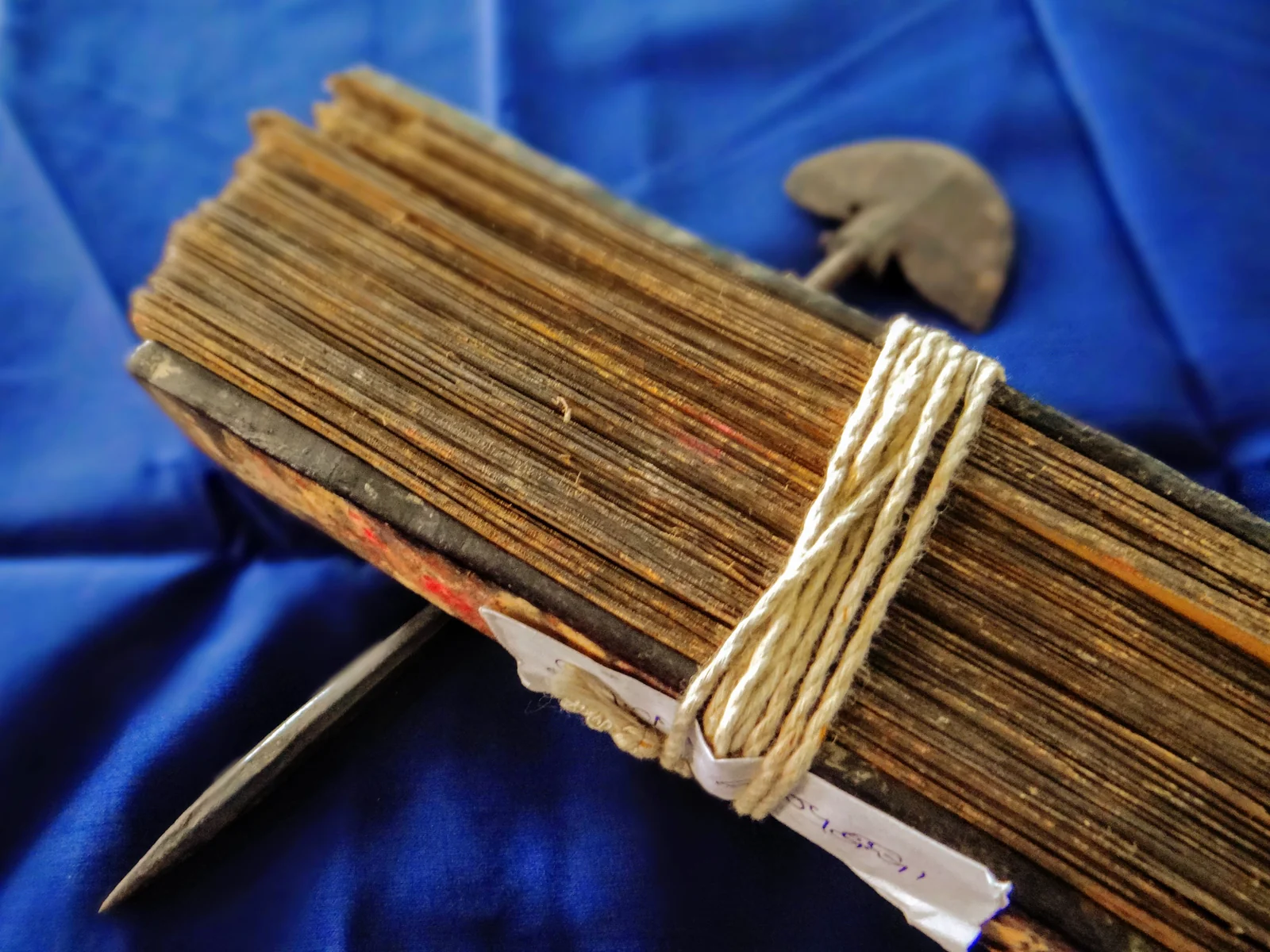An Odia palm-leaf manuscript beside a metal writing stylus.