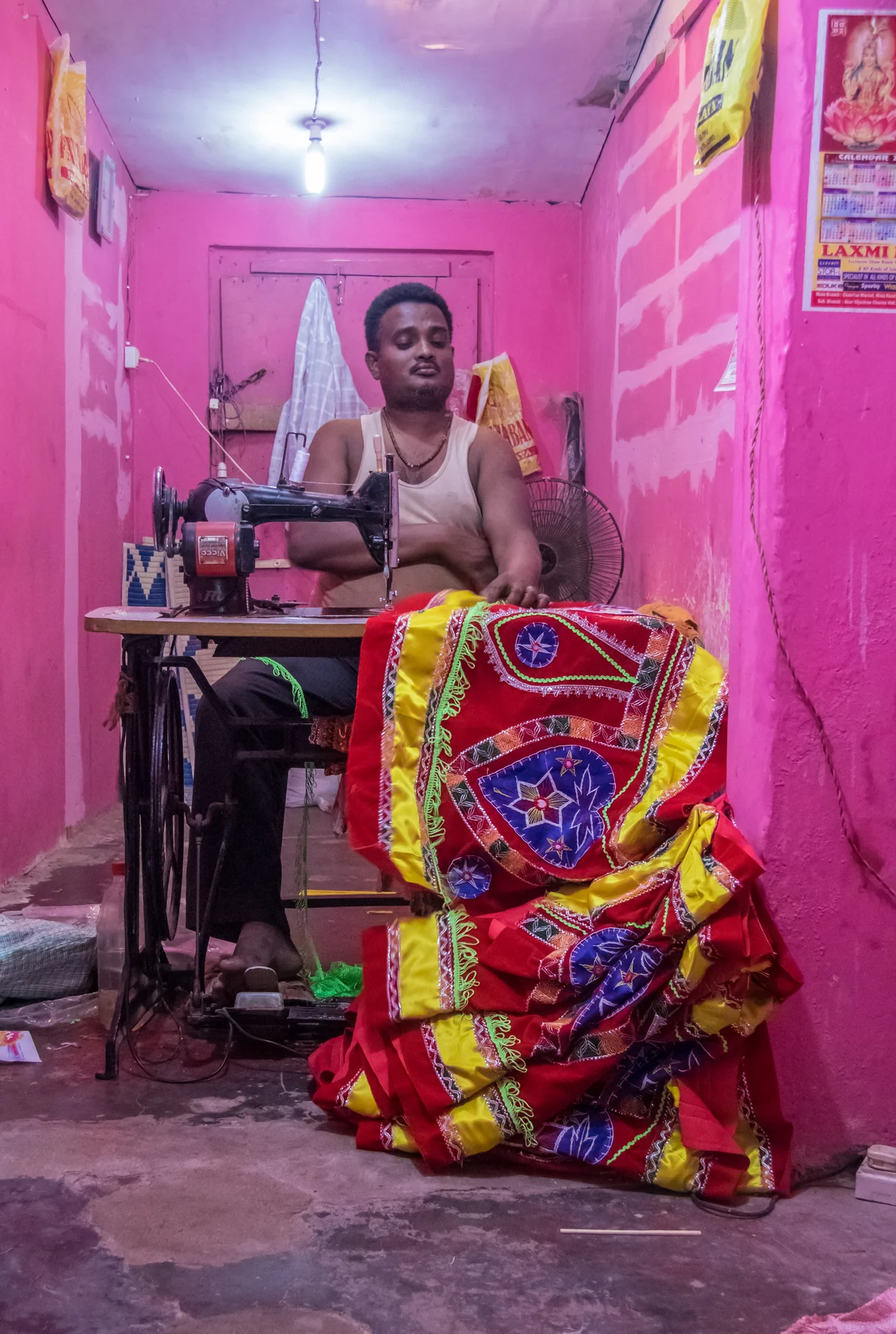 A craftsperson working at a sewing machine with a large red and yellow appliqué textile.