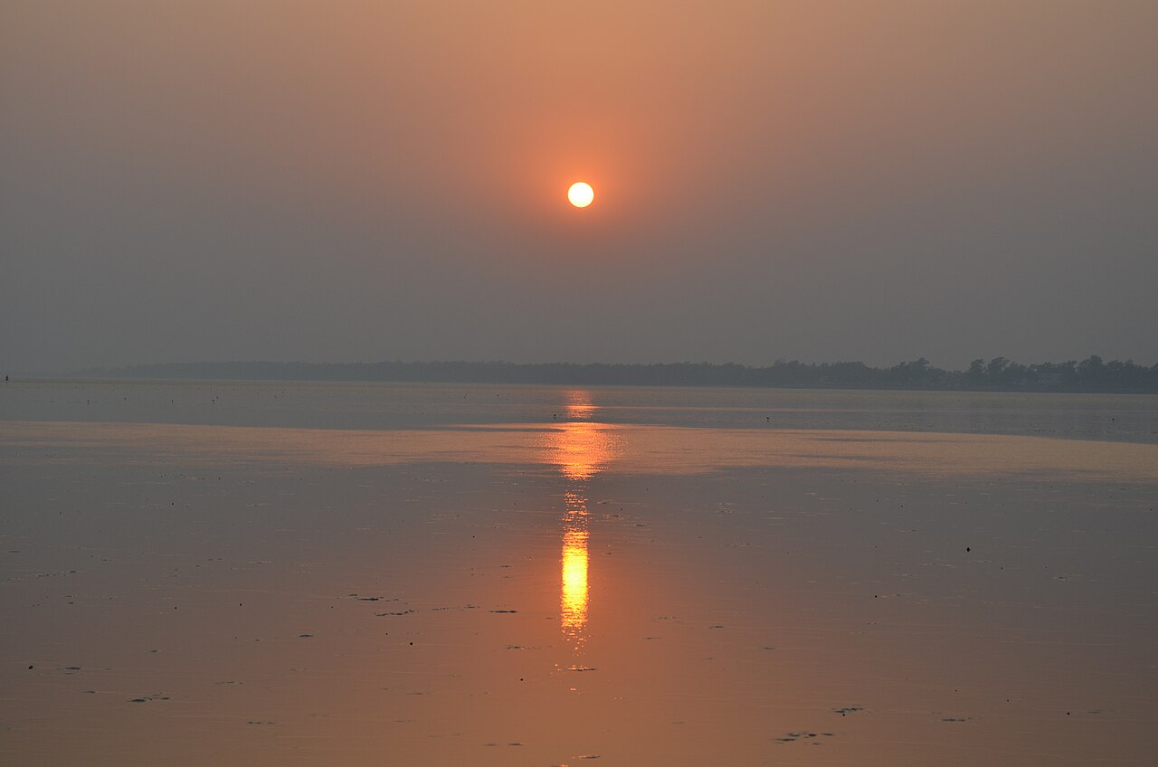 An orange sun reflected in the wet sand at Chandipur.