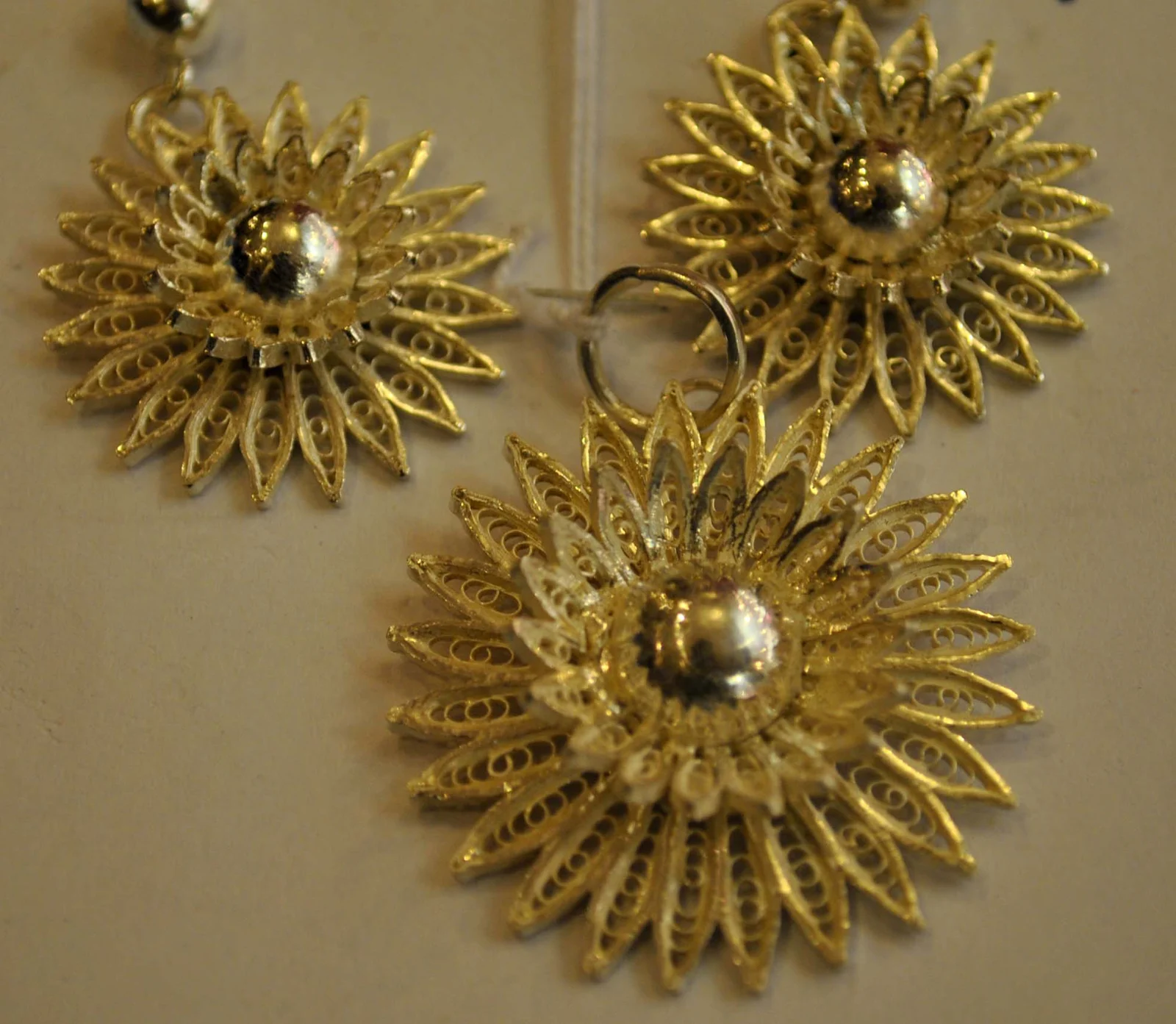 A pendant and earrings with intricate looping filigree patterns.